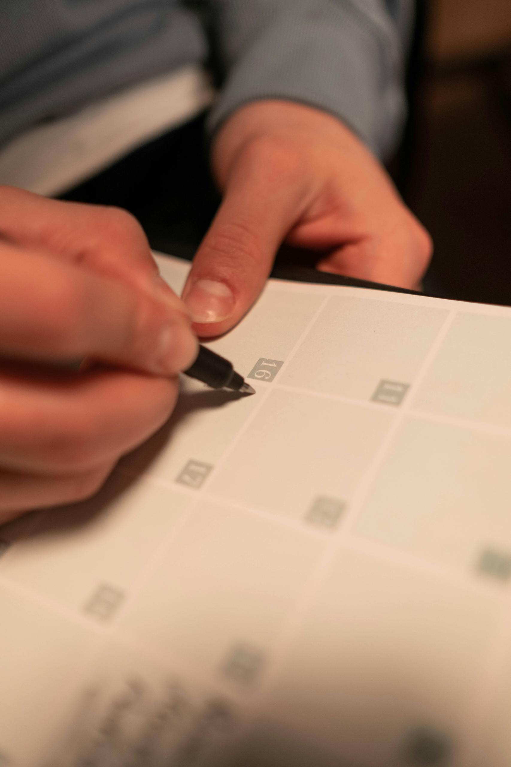Close-up of a hand writing on a calendar, planning future events.